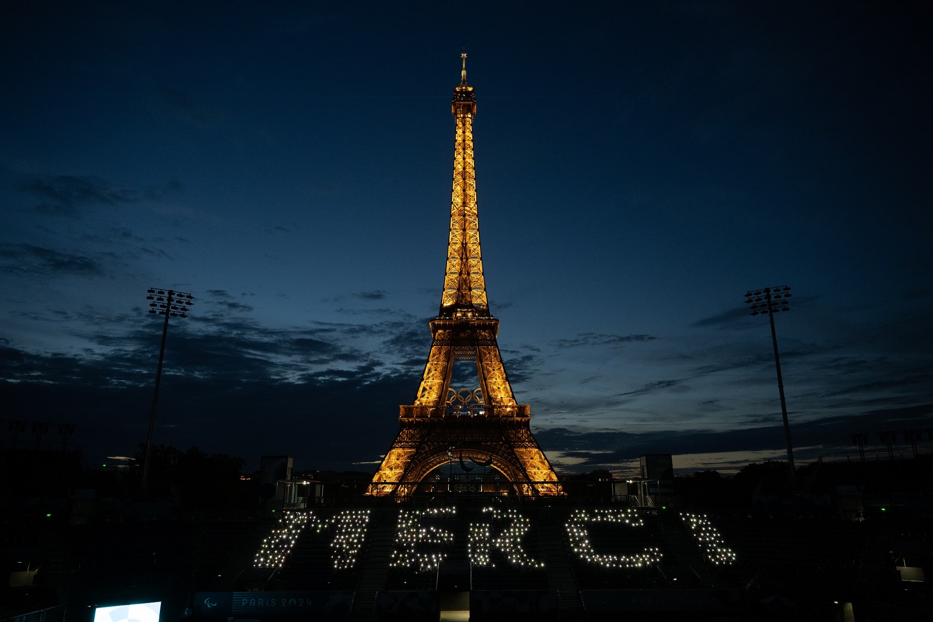 La Tour Eiffel illuminée de nuit avec le mot 'MERCI' formé en lumières blanches devant, lors des Jeux Olympiques et Paralympiques de Paris 2024